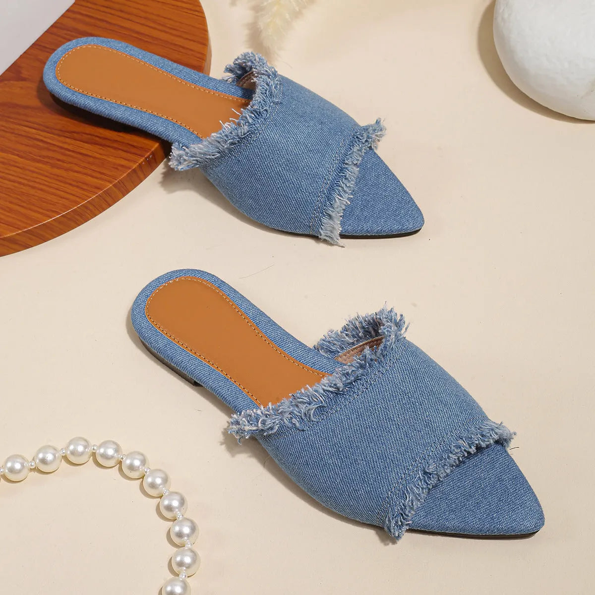 Women's denim flat slippers with tassel decoration and leather lining in apricot colour.