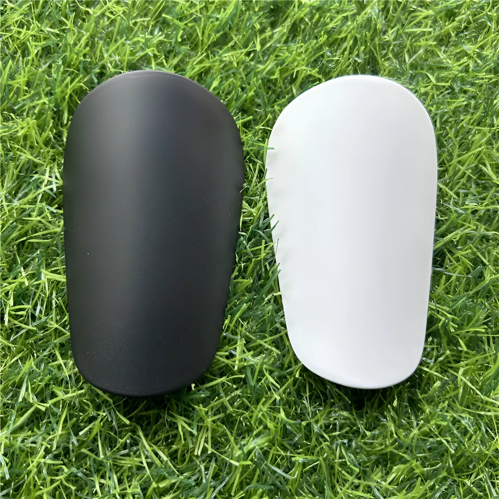 Extra small mini football shin guards measuring 8cm by 5cm in black and white plastic