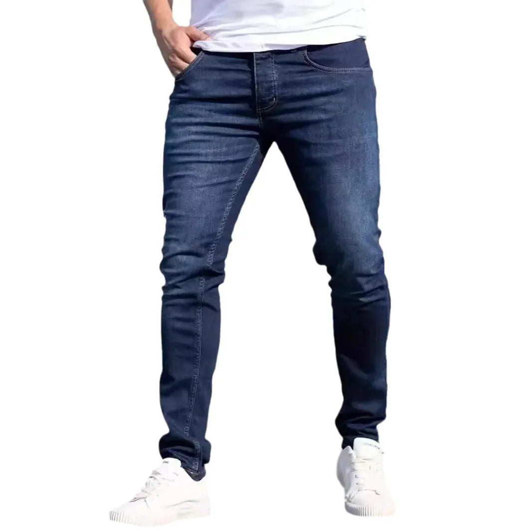 Dark blue men's slim fit casual jeans with mid waist and skinny leg style.