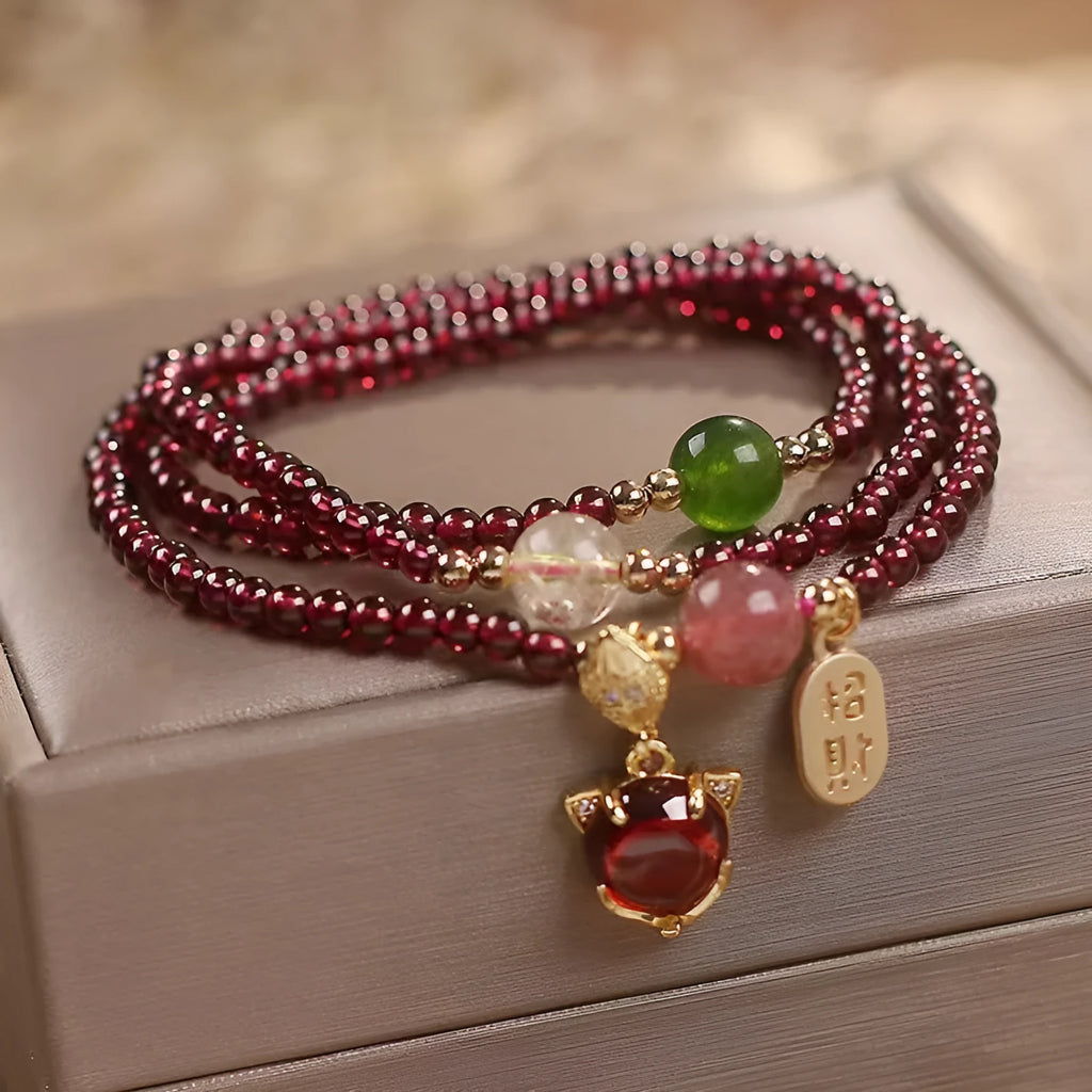 Purplish red garnet bead bracelet with a silver fox charm and adjustable rope fastening.