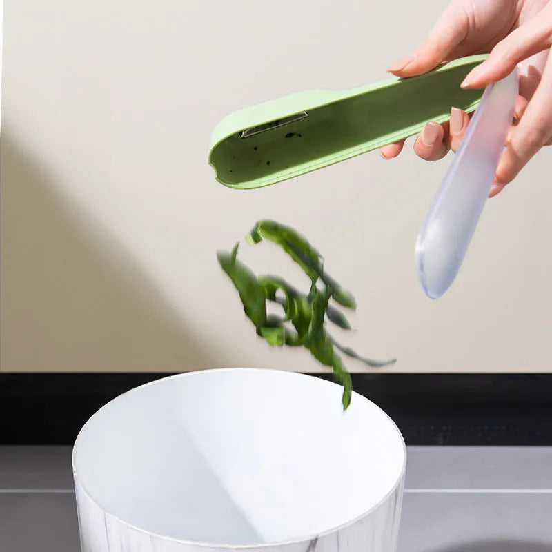 Dark green kitchen peeler with stainless steel blade inside its clear plastic storage tube