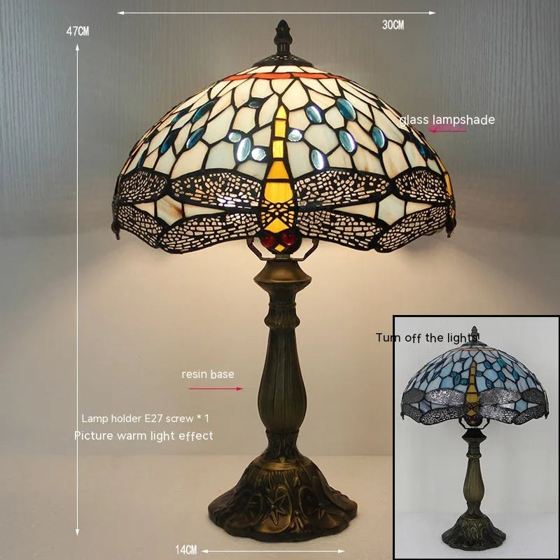 Tiffany style stone table lamp with blue dragonfly design on a bedside table.