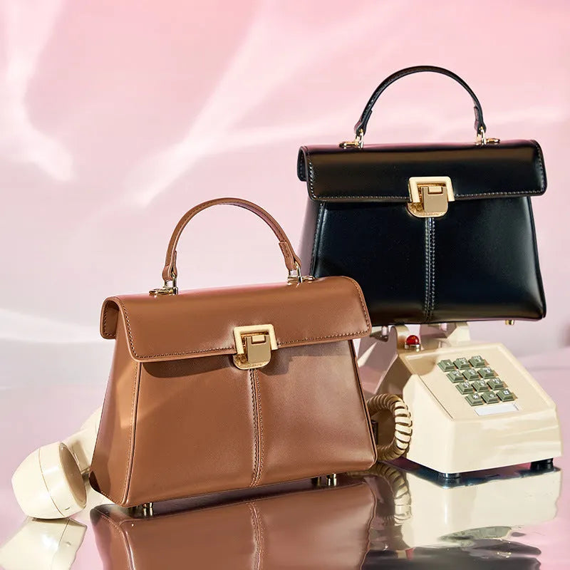 Women's black leather shoulder bag with vachette clasp showing organised interior compartments