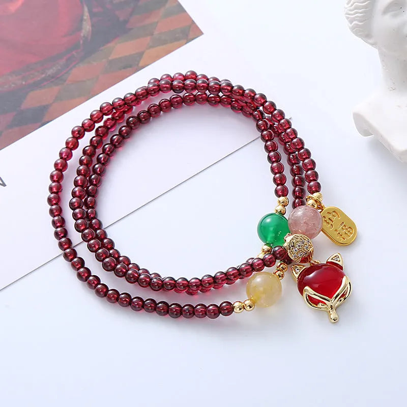 Purplish red garnet bead bracelet with a silver fox charm and adjustable rope fastening.