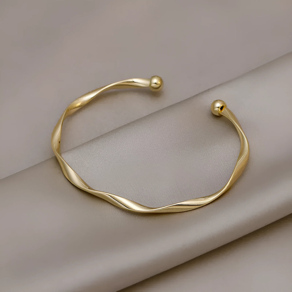 Gold alloy geometric twist bracelet with 6.2 cm inner ring diameter on white background