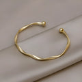 Gold alloy geometric twist bracelet with 6.2 cm inner ring diameter on white background