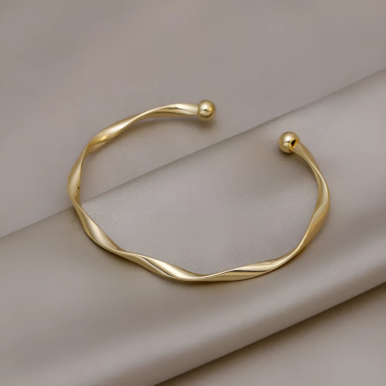 Gold alloy geometric twist bracelet with 6.2 cm inner ring diameter on white background