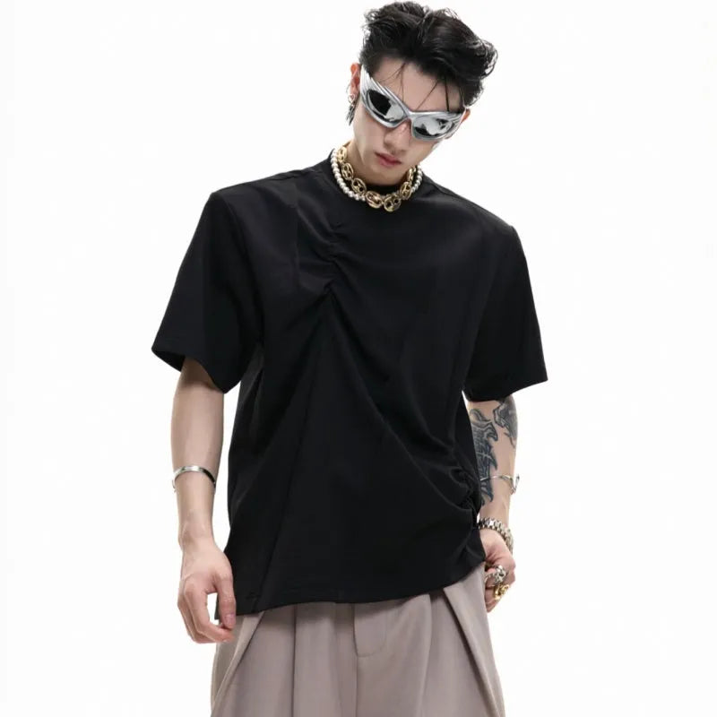 Man wearing a loose grey cotton T-shirt with three-dimensional pleated detailing on the front.