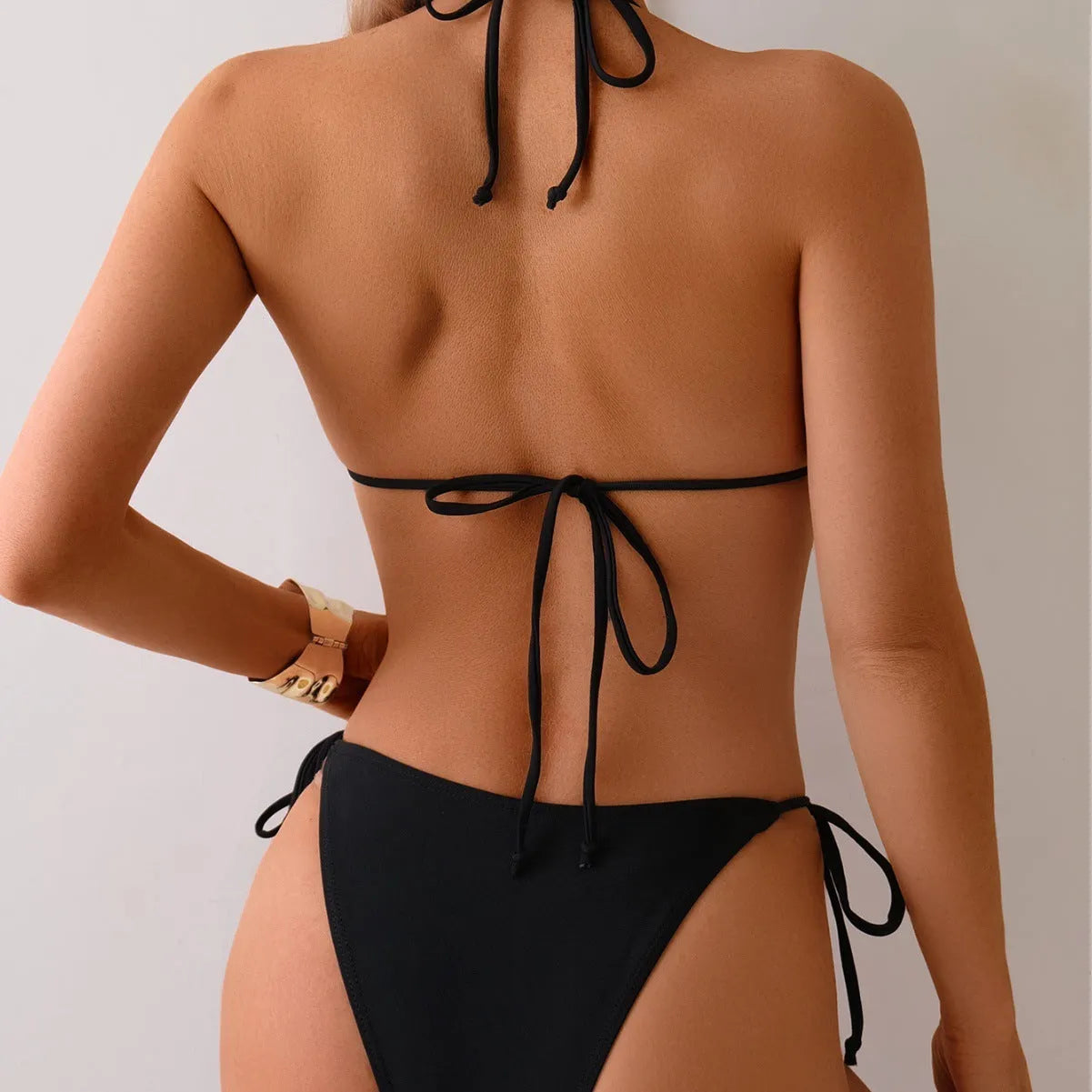 Black women's bikini swimsuit with metal bead decoration on a split-style design.