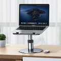Silver aluminium adjustable laptop stand with rotating base and non-slip pads on a desk.