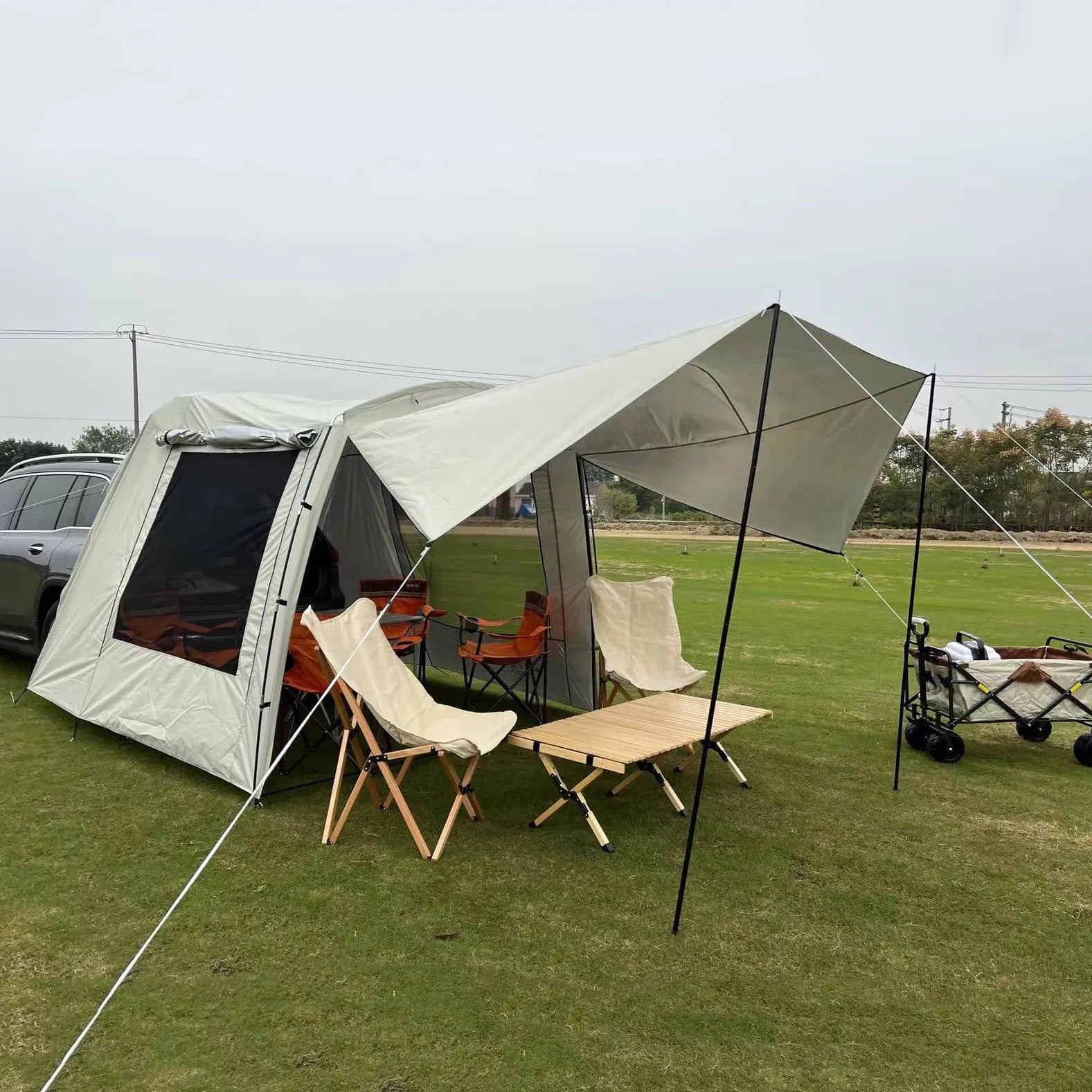 Car tail extension tent set up at a campsite with rear access, showing 190T silver-coated anti-UV fabric and screen windows.