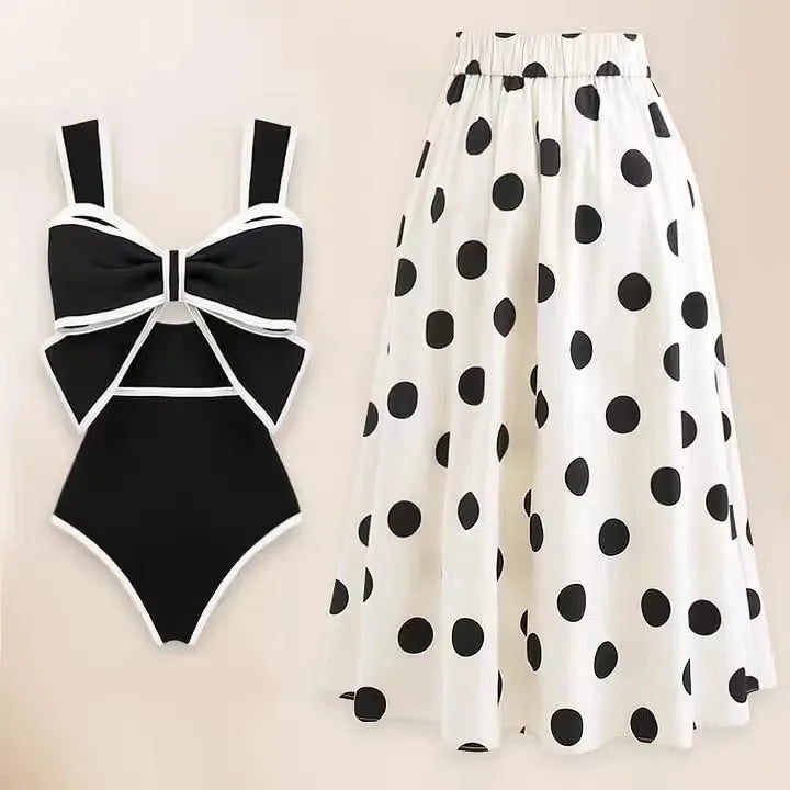 Women's black one-piece swimsuit with a white flared skirt and a bow detail.