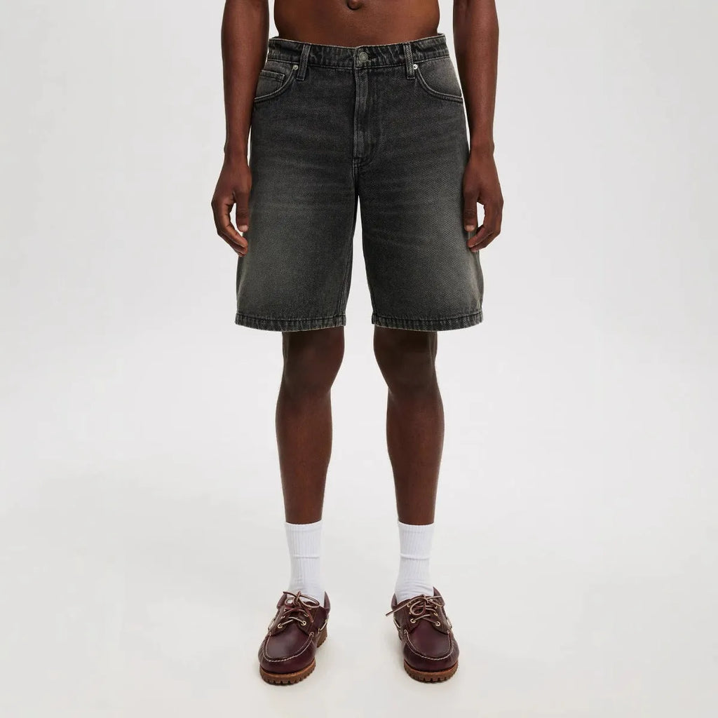 Man wearing loose fit light blue straight-leg denim jeans, a casual street style summer outfit.