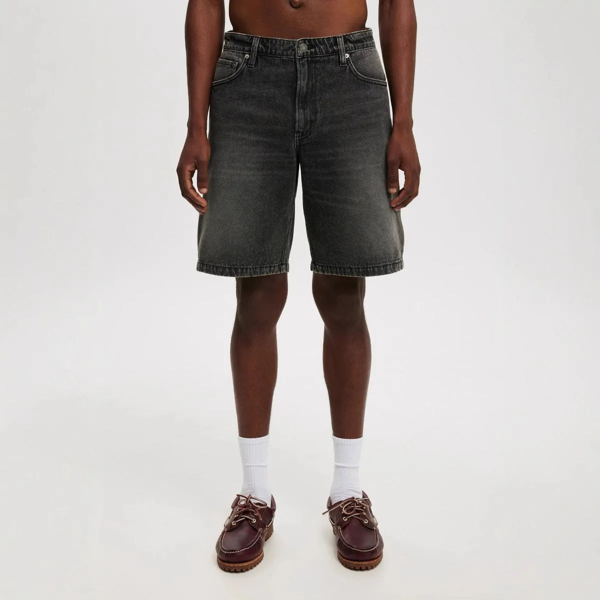 Man wearing loose fit light blue straight-leg denim jeans, a casual street style summer outfit.