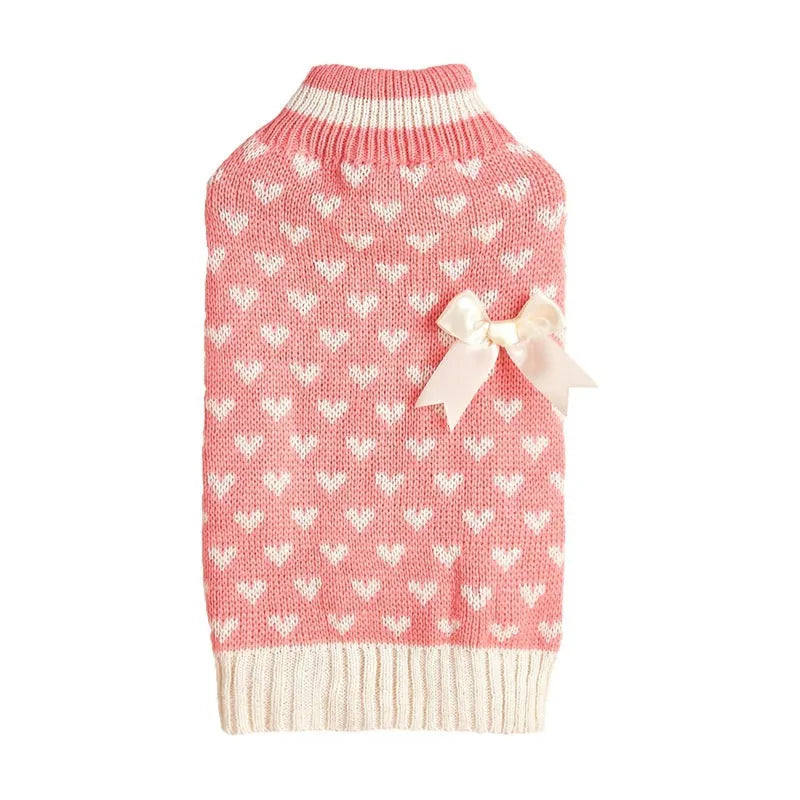 Small dog wearing an acrylic sweater with pink bow and love heart design