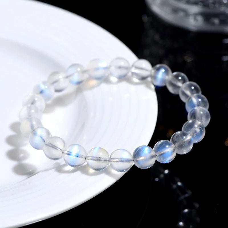 Natural blue moonlight cream body crystal bracelet on wrist, showing single strand of polished beads.