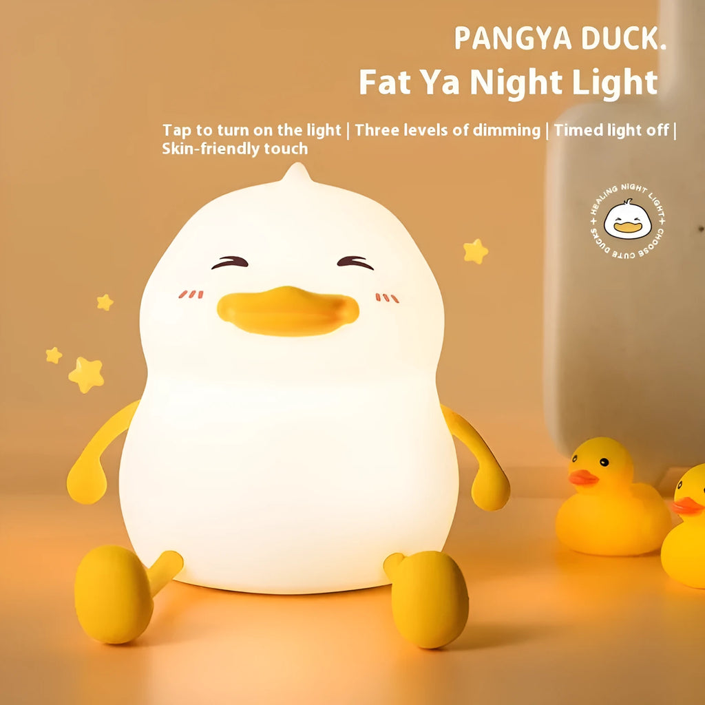Chubby white silicone night lamp on a desk holding a mobile phone, showing soft LED glow.