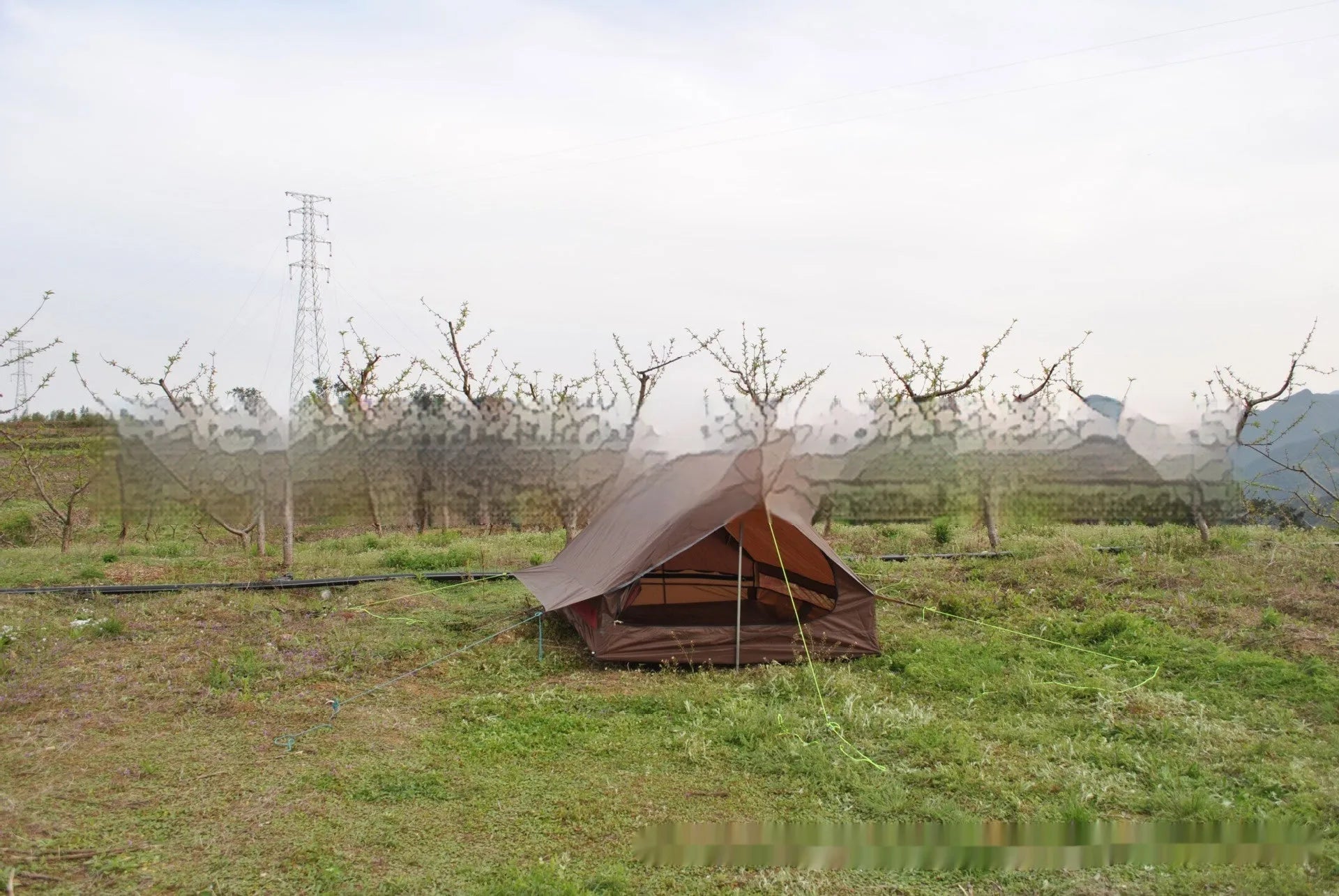 Brown A-line cabin tent pitched using hiking poles with aluminium ground nails and fluorescent wind ropes