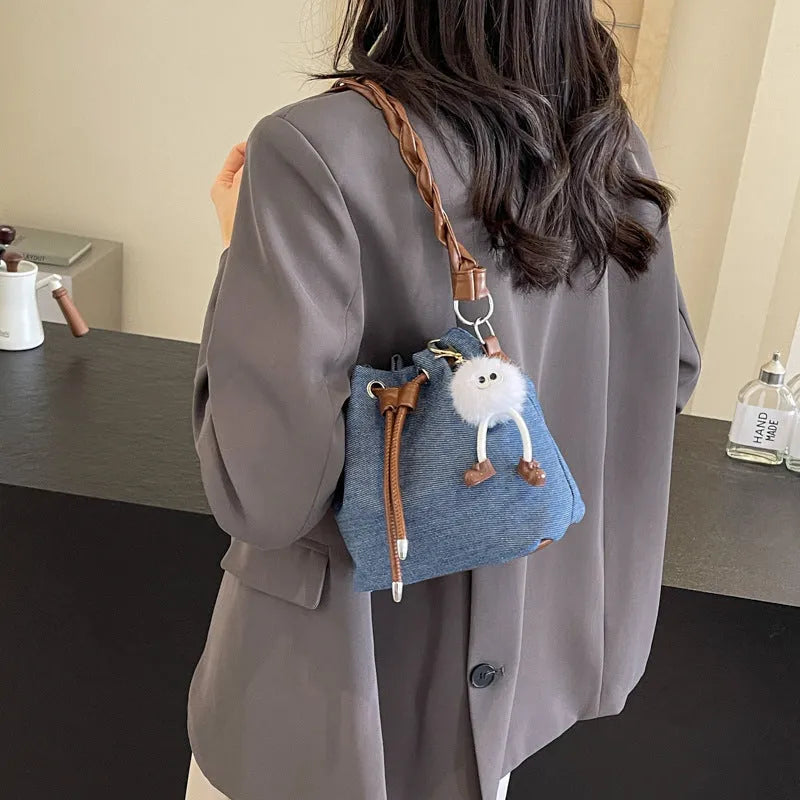 Blue cross body bucket bag with synthetic leather lining and hanging drop ornaments
