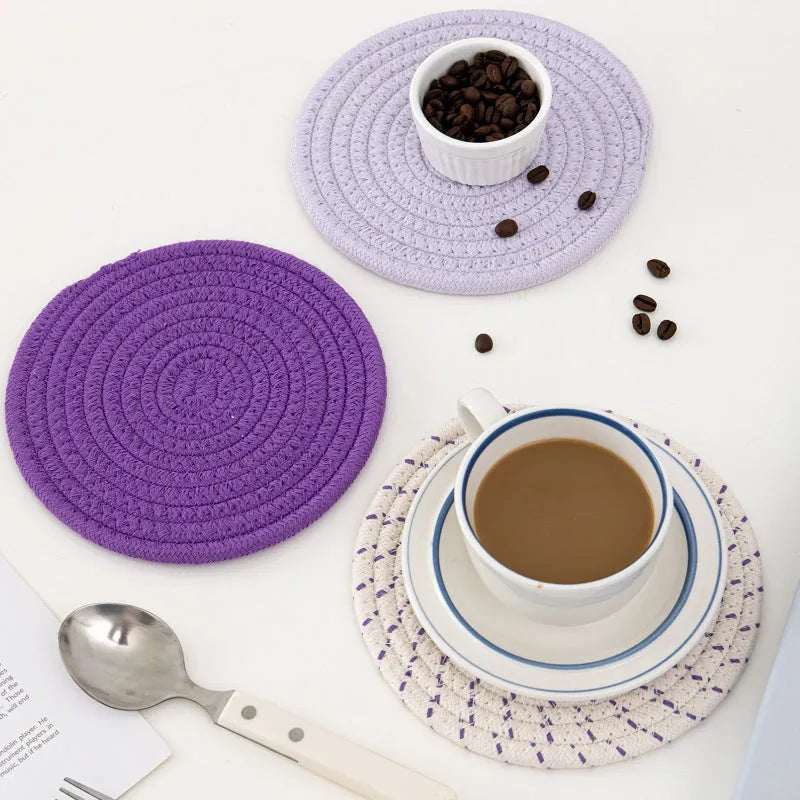 Three round blue cotton cord coaster placemats on a wooden table.