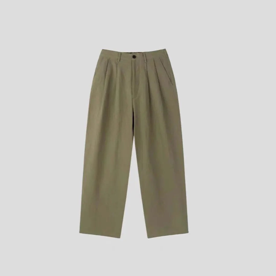 Man wearing apricot-coloured wide-leg cotton linen suit trousers with a pencil leg opening.