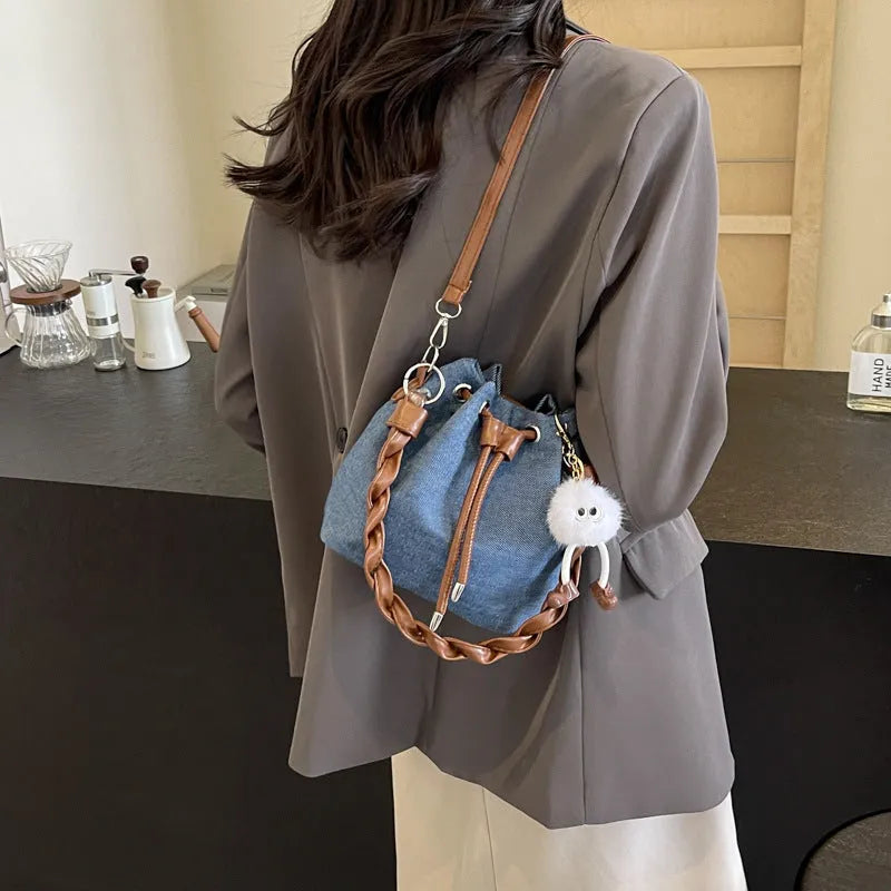 Blue cross body bucket bag with synthetic leather lining and hanging drop ornaments