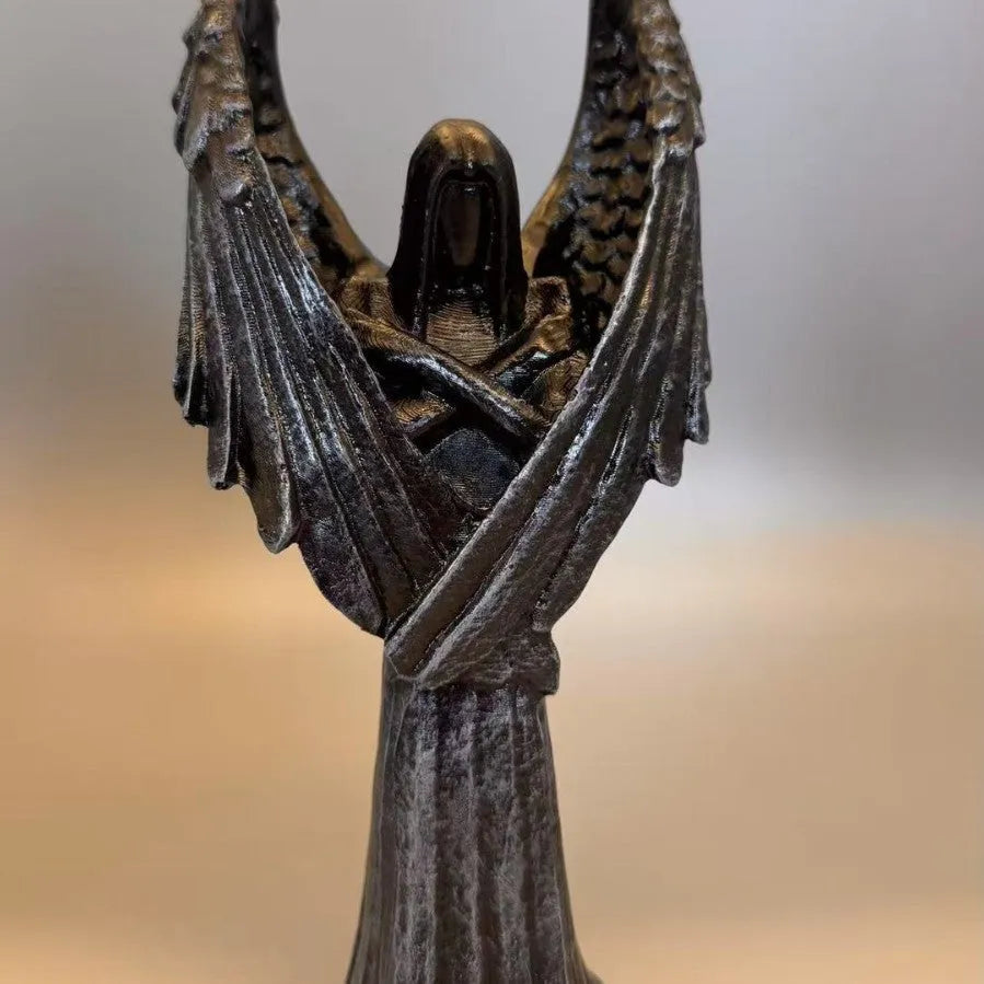 Small dark angel resin statue ornament on a table, showing detailed wings and robe.