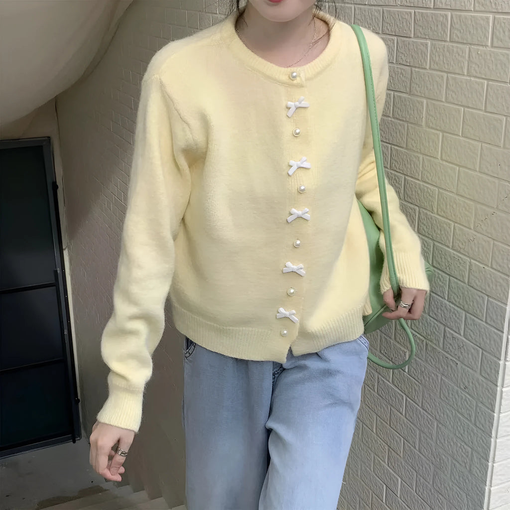 Women's light blue cashmere blend cardigan with white bow and pearl button detail on front.