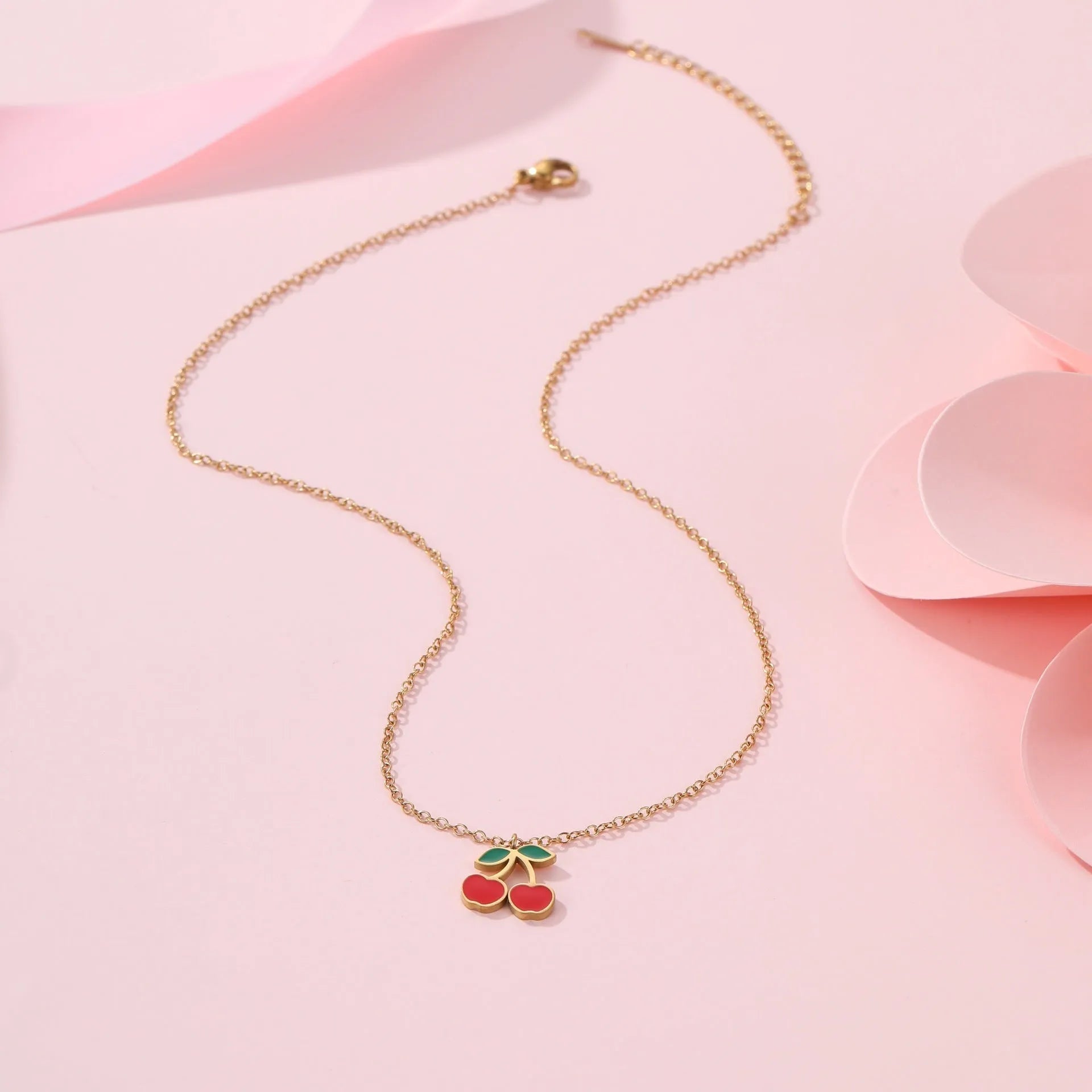 Complete cherry jewellery set showing stainless steel necklace, bracelet, earrings, and ring pieces with electroplated colour finishes