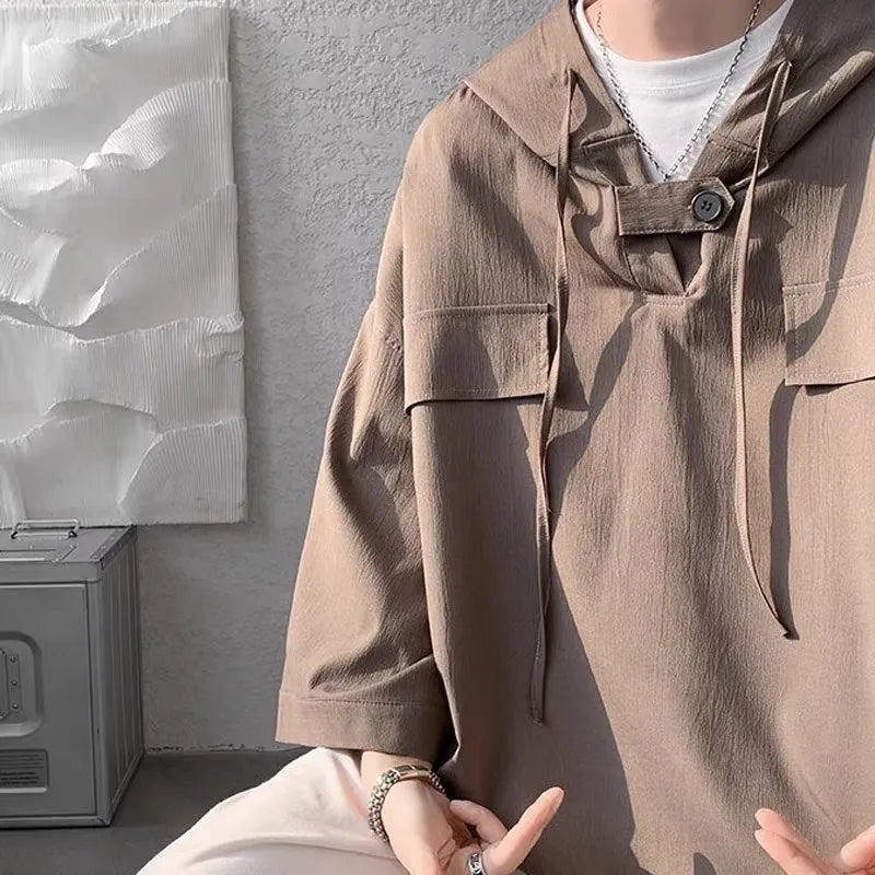 A man wearing a loose grey hooded short sleeve t-shirt on a casual day.
