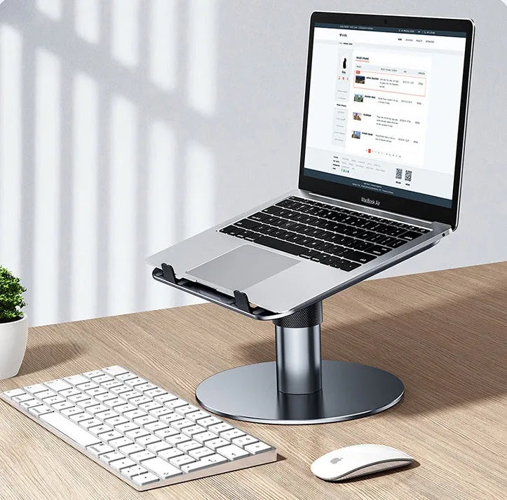 Silver aluminium adjustable laptop stand with rotating base and non-slip pads on a desk.