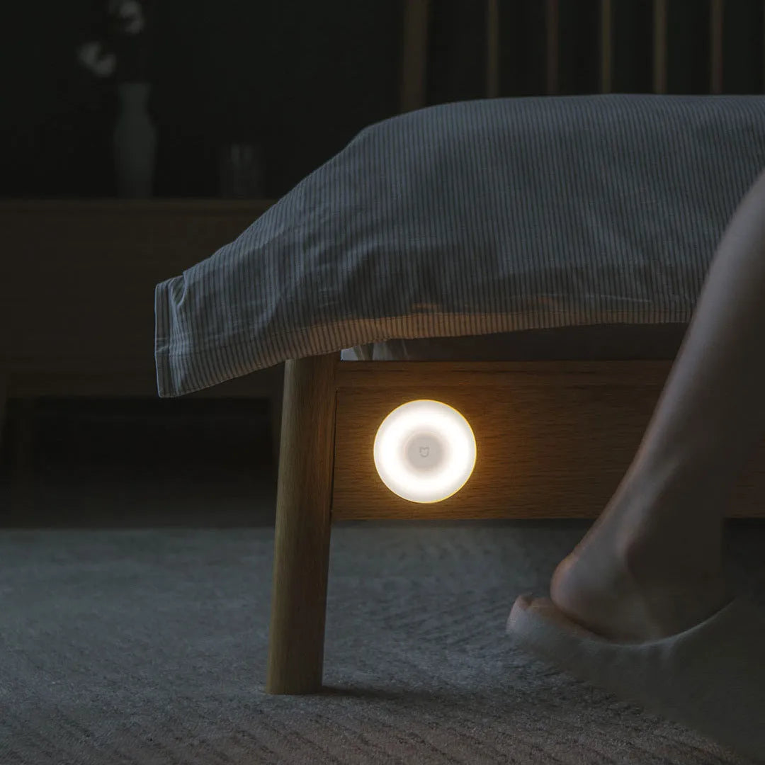 White cube-shaped Mijia bedside night light with motion sensor and Bluetooth on a wooden table.