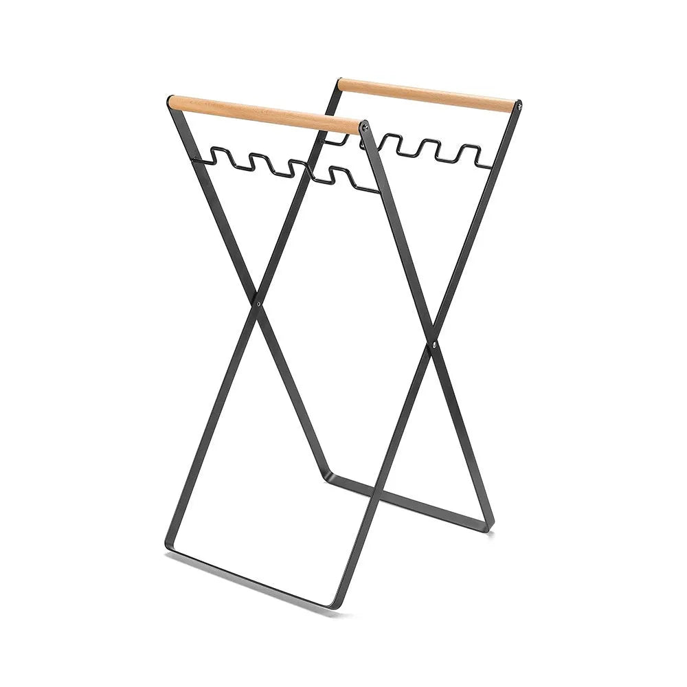 Black outdoor folding trash rack with wooden handle holding a white bin bag open.