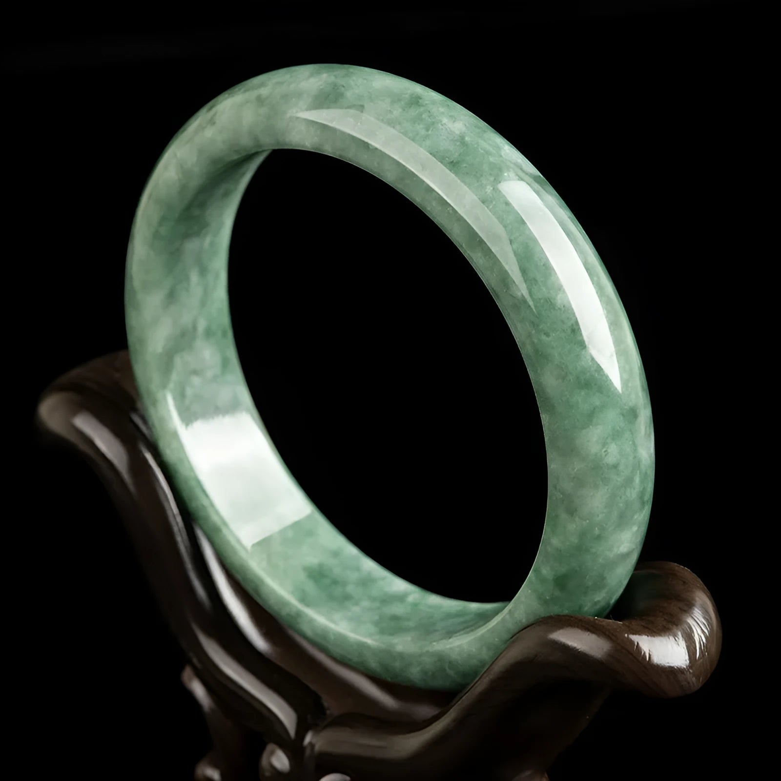 Dark pea green jade bracelet on a wrist, showing its simple band style and natural colour.