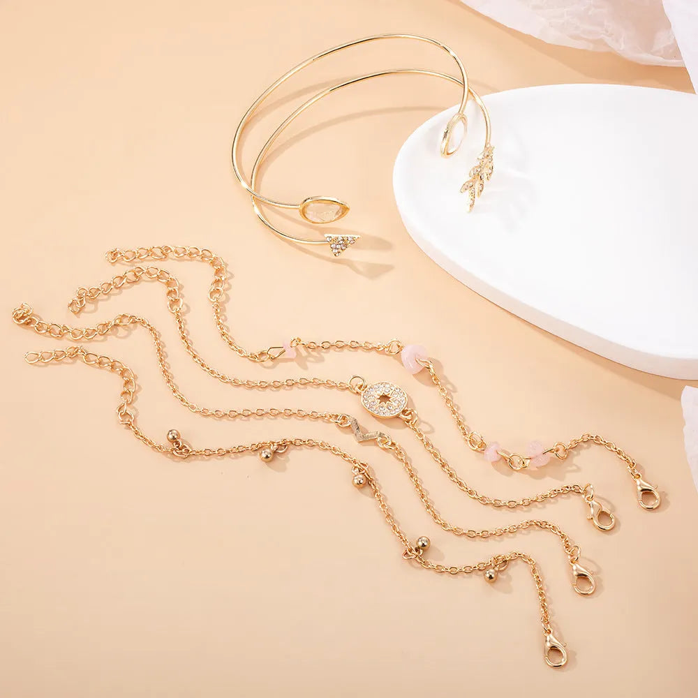 Gold-coloured zinc alloy bracelet set with arrow and V-shaped water droplet design elements