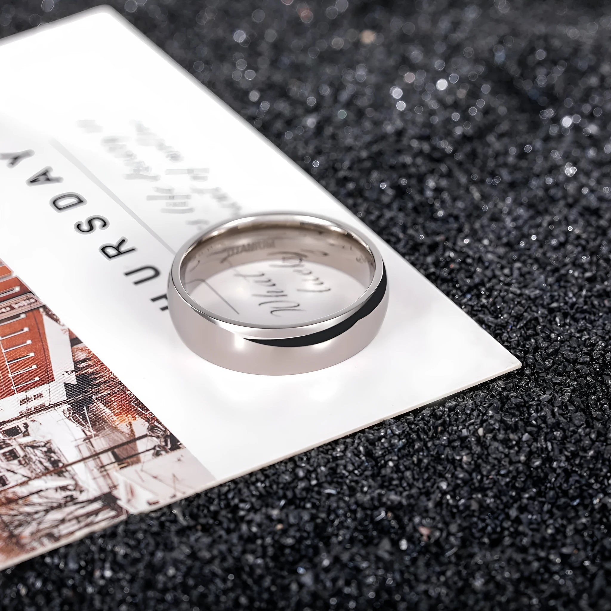 A simple silver titanium steel ring on a finger, showing the band's width and uniform ground finish.