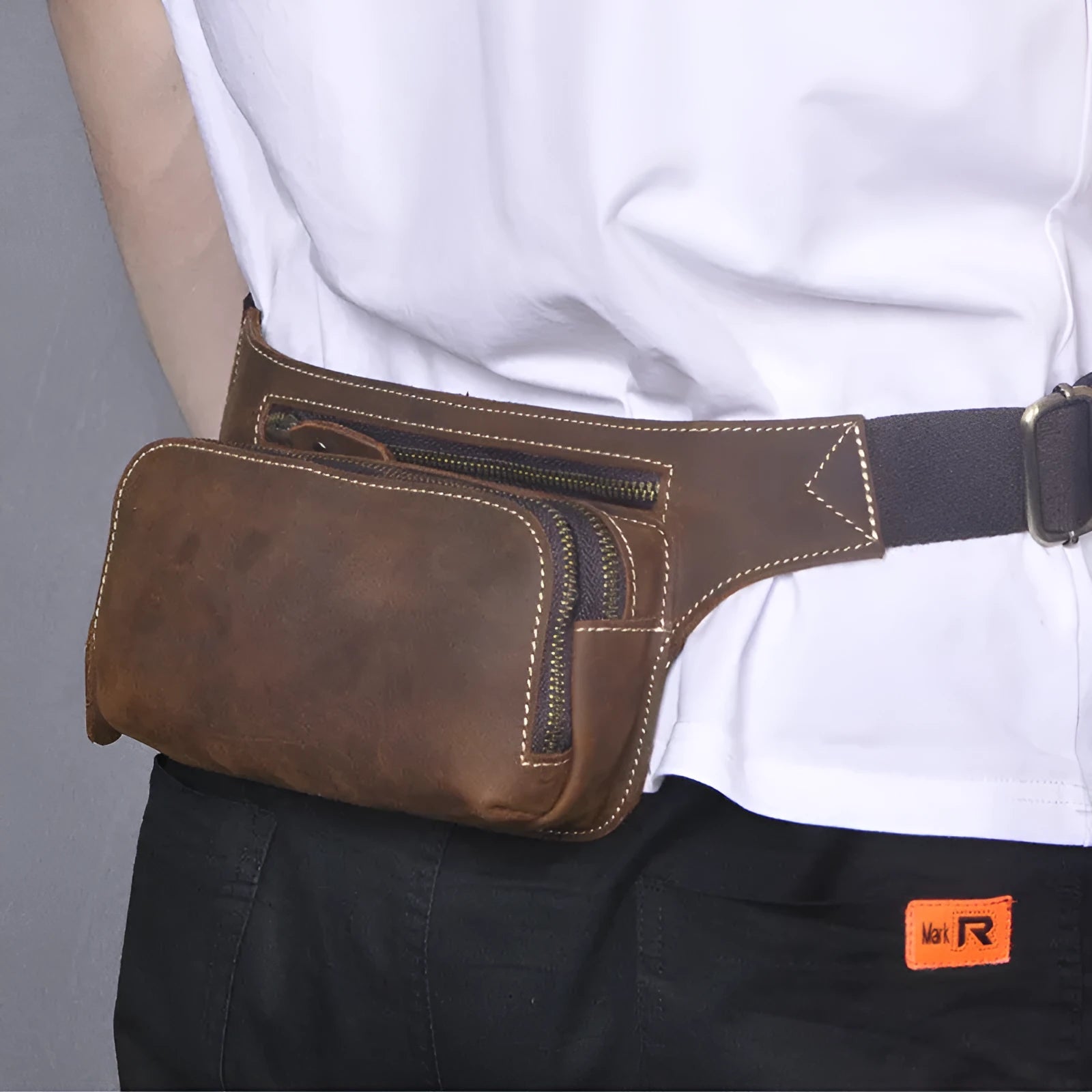 Brown cowhide leather men's sports waist bag with zip, shown with phone in internal pocket.