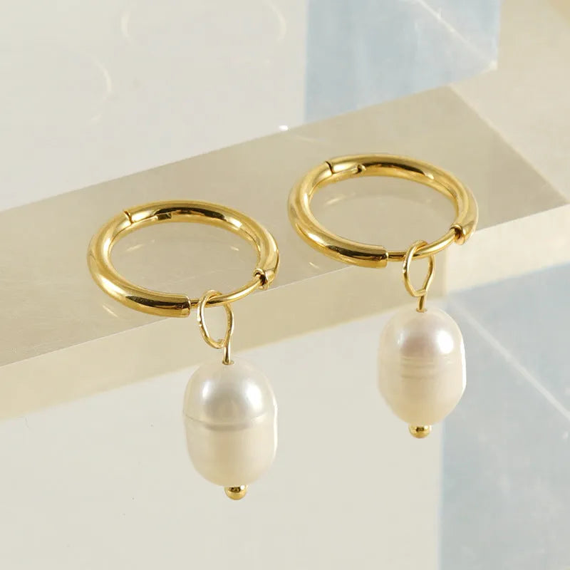 A pair of gold-coloured geometric stud earrings with a single pearl accent on each.