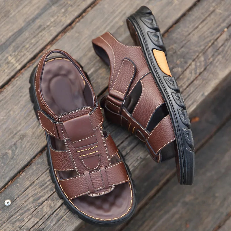 Men's brown cowhide leather sandals with velcro strap and open toe on a beach background