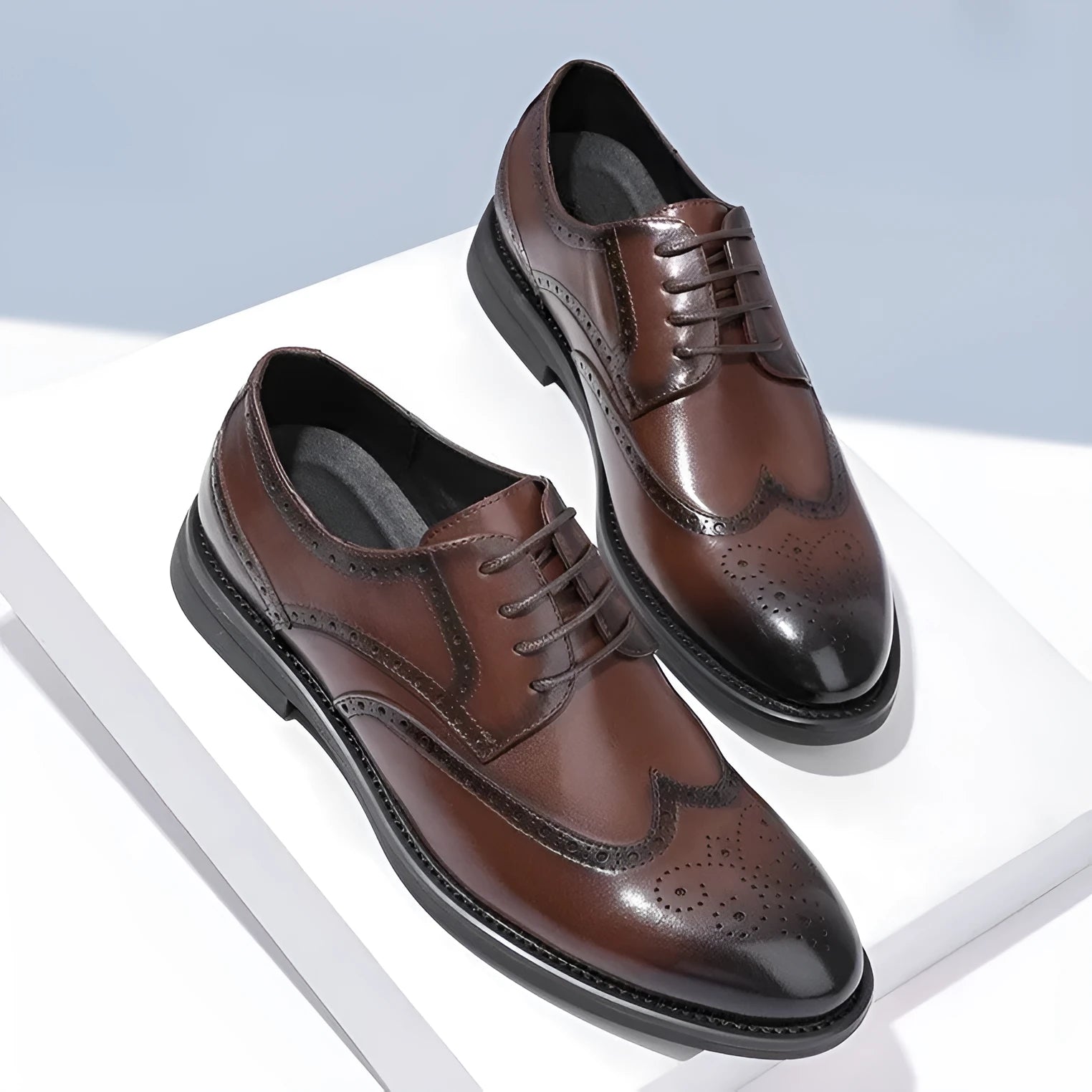 Men's black and brown brogue leather shoes for business style on a plain background.