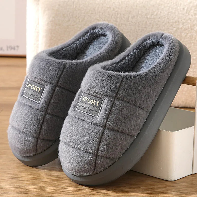 Men's grey and brown plaid rabbit hair winter slippers with a thick sole on a wooden floor.