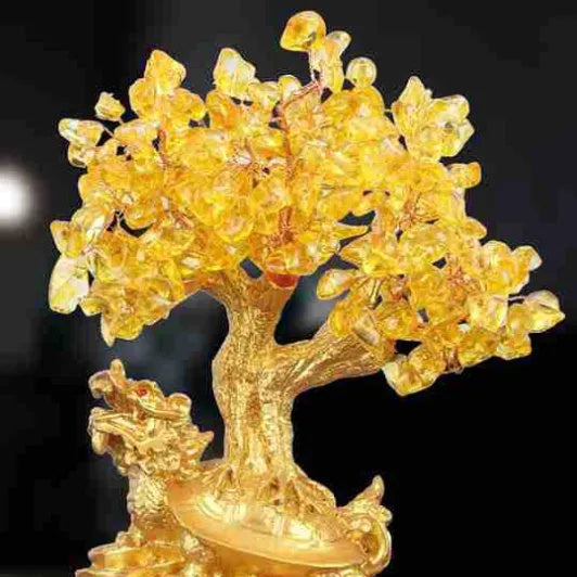 Citrine-coloured resin turtle money tree ornament on a neutral background.