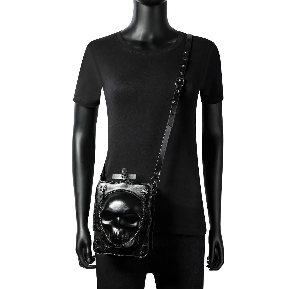 Black mini skull shoulder bag with 3D embossed design, chain strap, and vertical square shape for Gothic fashion.
