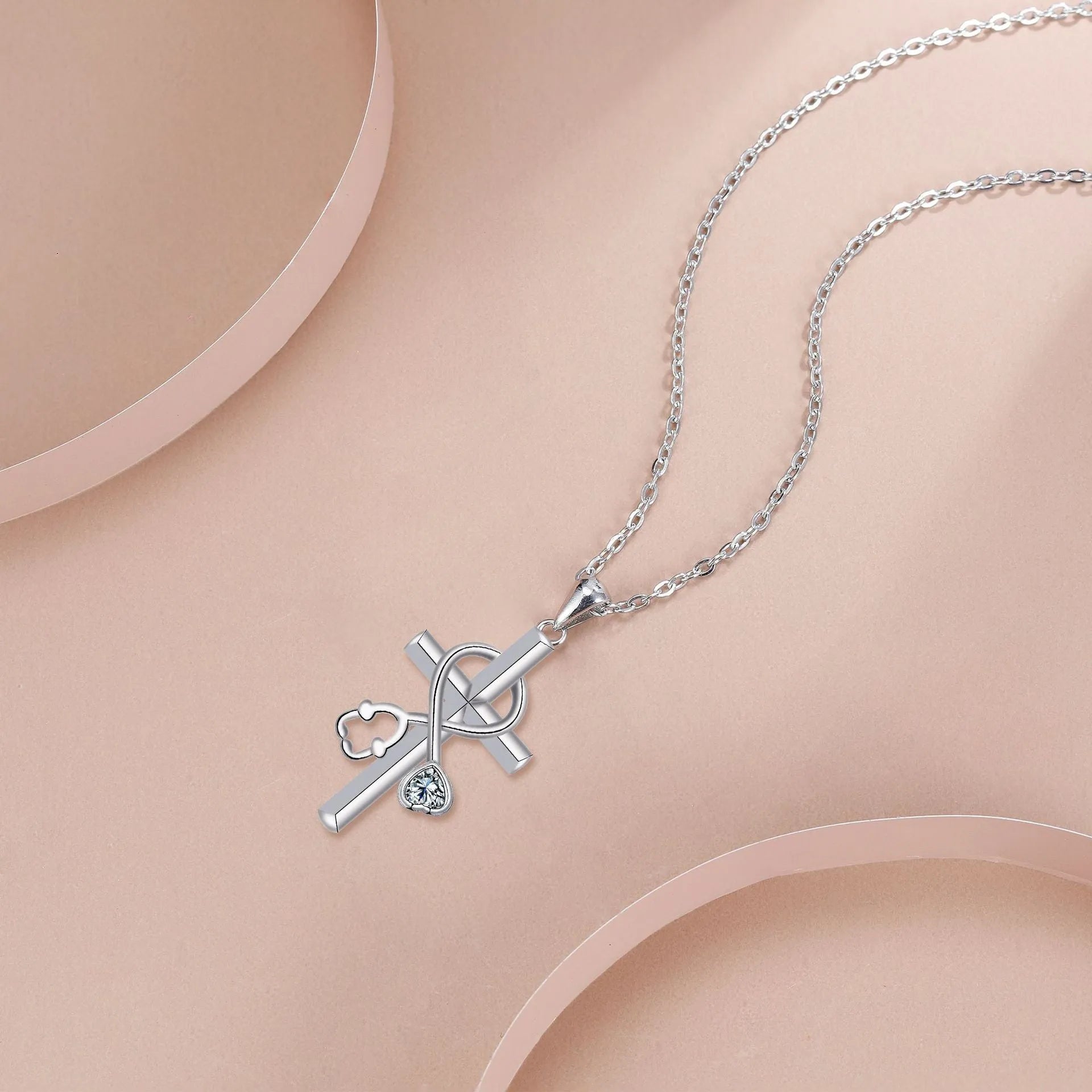 Silver-coloured women's necklace with a pendant shaped as a cross combined with a stethoscope.