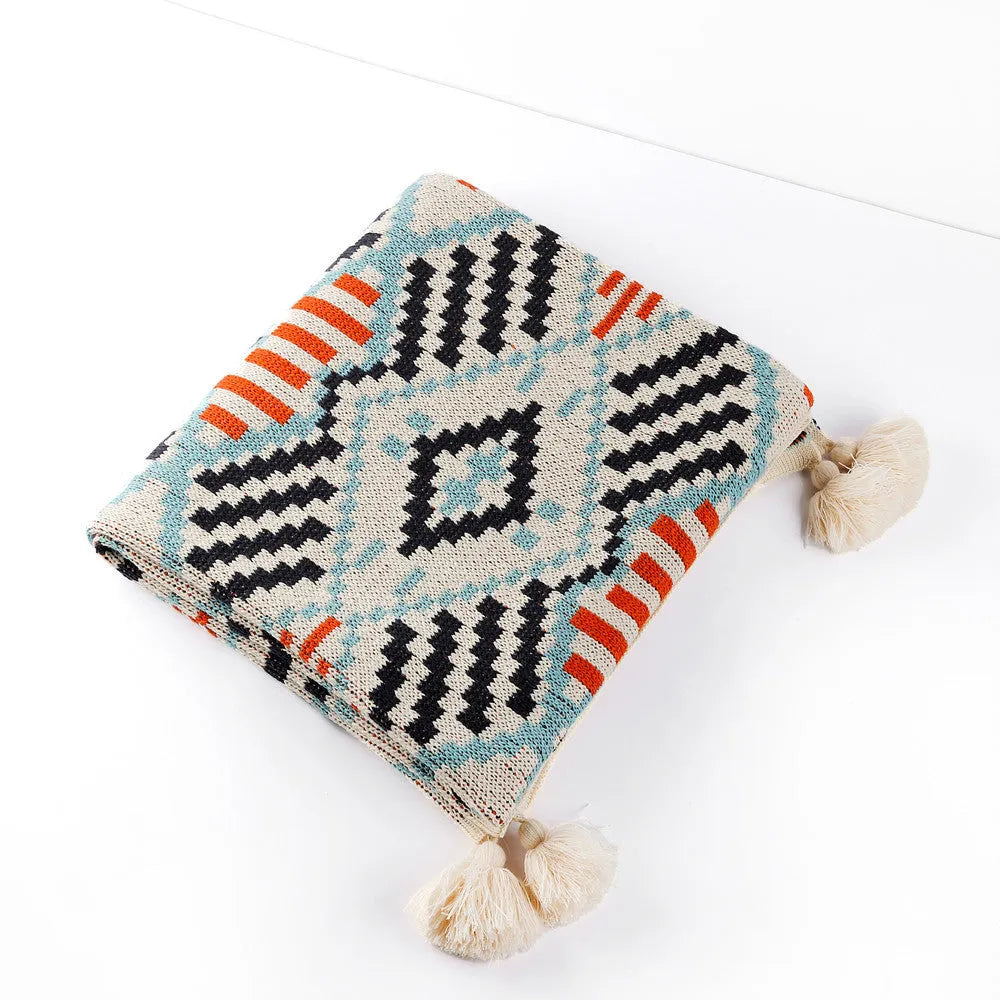 Bohemian-style acrylic sofa blanket with tassel trim shown in a beige and orange colour.