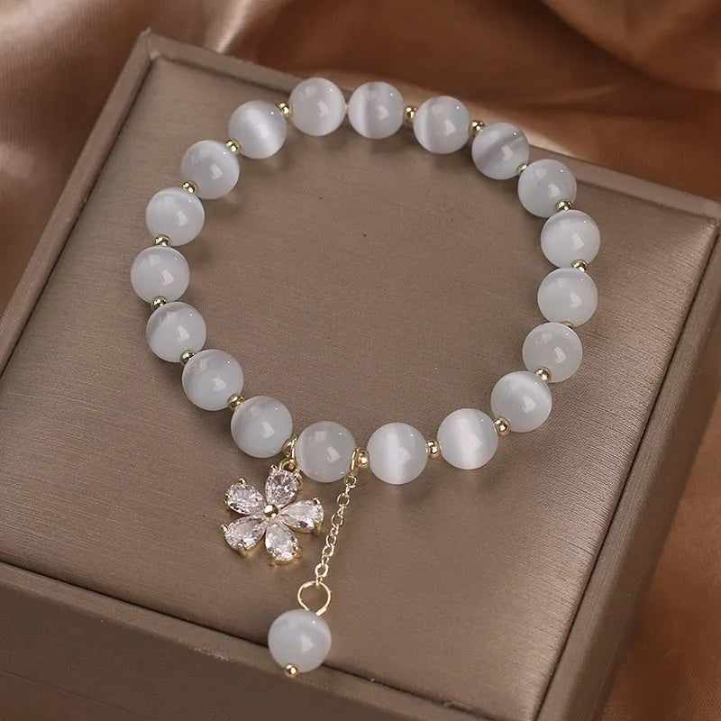 Single loop women's bracelet with white cat's eye stone, small flower tassel, and morganite safety buckle pendant.