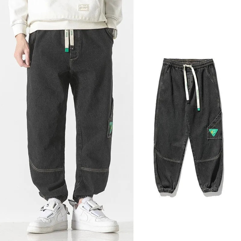 Men's loose-fit tapered cotton trousers in black, shown in a casual setting.