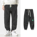 Men's loose-fit tapered cotton trousers in black, shown in a casual setting.