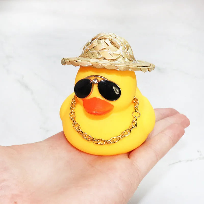 Yellow cartoon duck car ornament wearing a straw hat, with miniature sunglasses accessory.