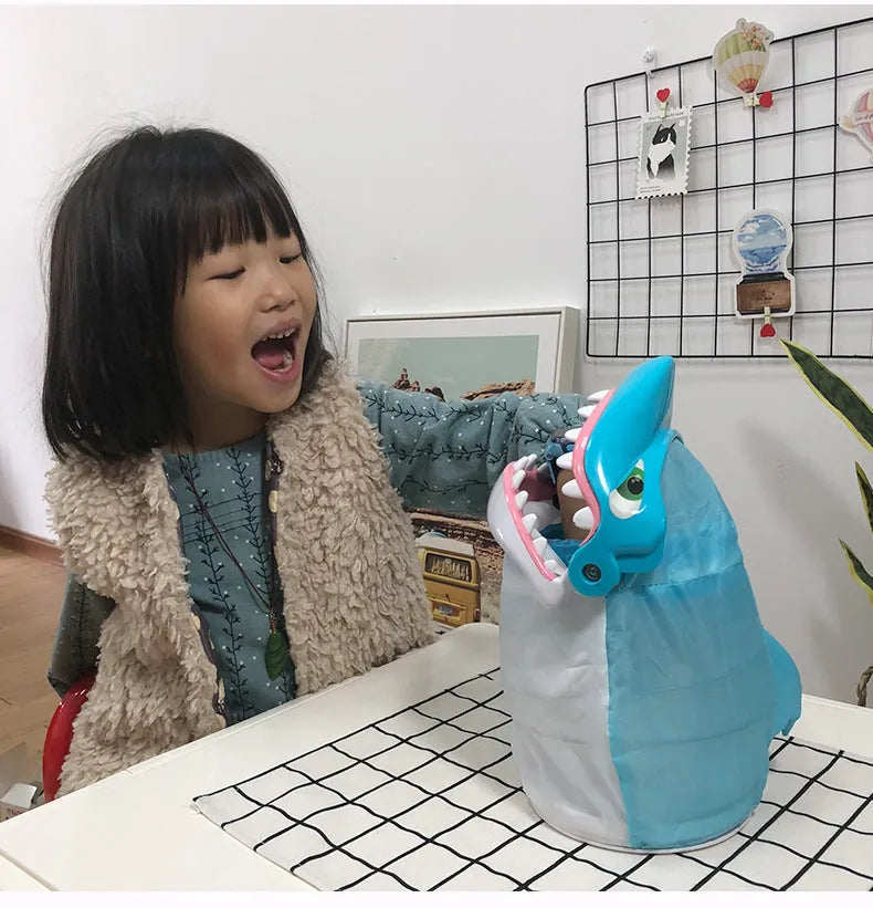 Great white shark tricky toy with small plastic fish inserted in its mouth on a tabletop
